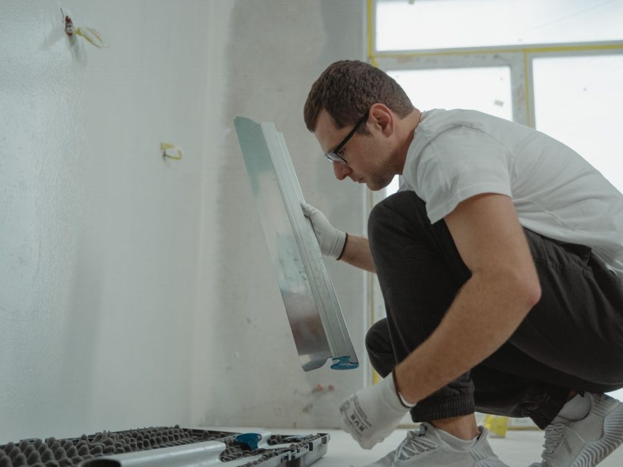 Fliesenleger richtet eine Wandfliese mit Kelle und Wasserwaage aus